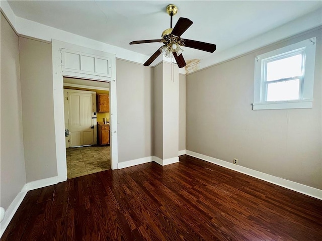 empty room featuring ceiling fan, baseboards, and wood finished floors