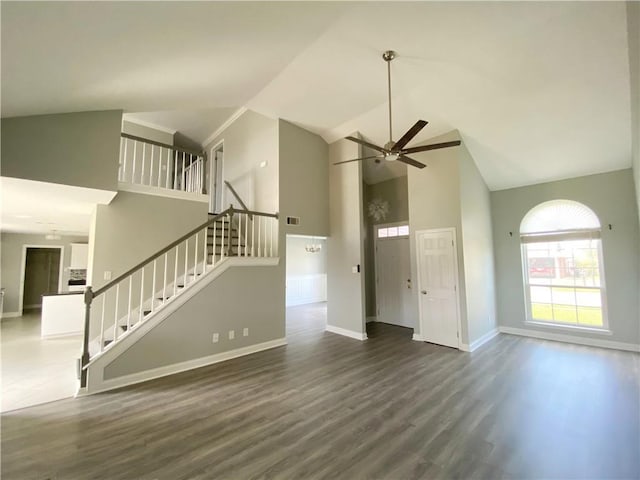 unfurnished living room with stairway, wood finished floors, baseboards, high vaulted ceiling, and ceiling fan