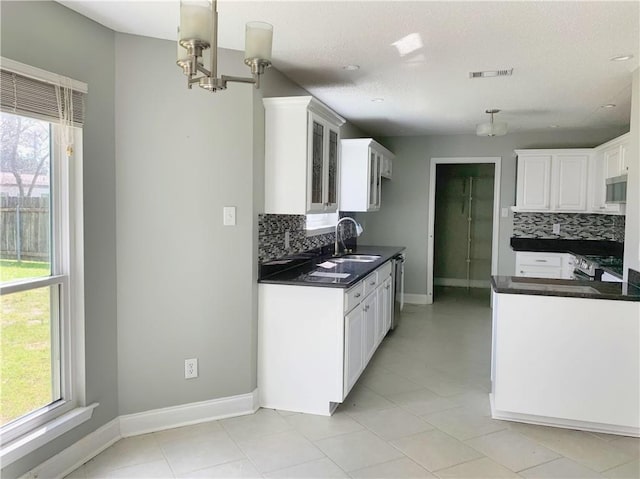 kitchen with visible vents, a sink, appliances with stainless steel finishes, dark countertops, and a wealth of natural light