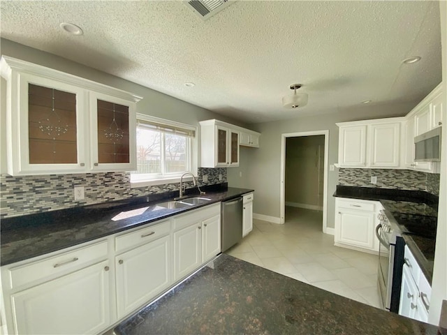 kitchen featuring visible vents, a sink, appliances with stainless steel finishes, white cabinets, and glass insert cabinets