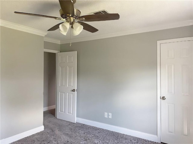 carpeted spare room with visible vents, baseboards, a ceiling fan, and crown molding