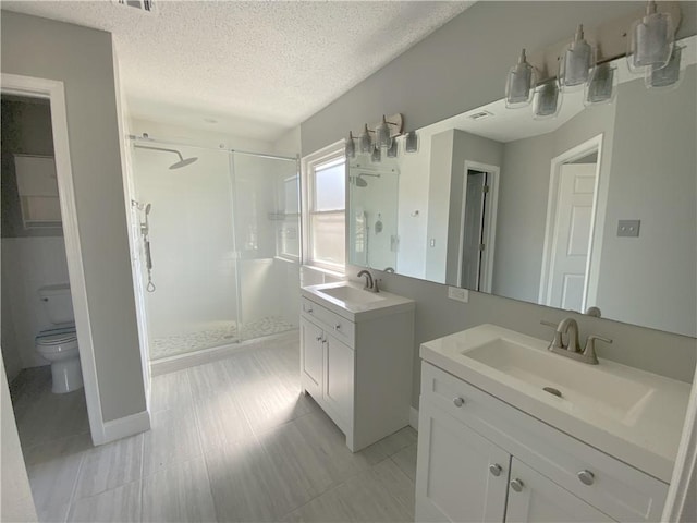 bathroom with a sink, a textured ceiling, two vanities, and a stall shower