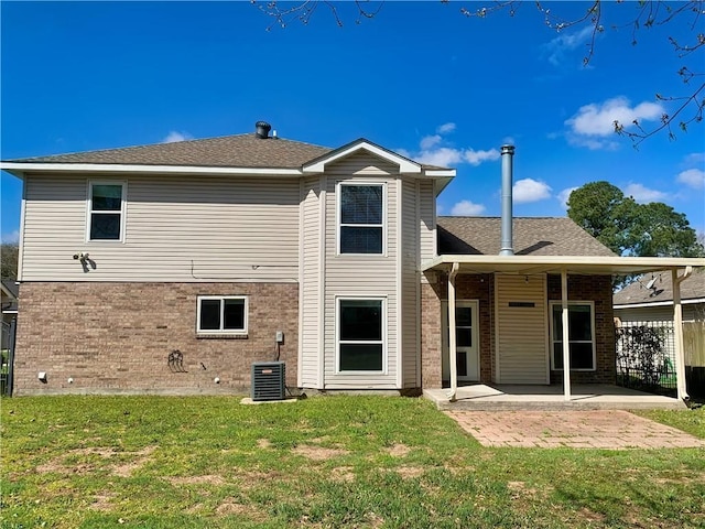 back of house with a patio area, a lawn, and brick siding