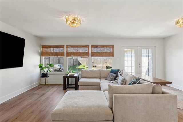 living area with wood finished floors, french doors, and baseboards