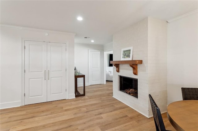 living room featuring a brick fireplace, baseboards, ornamental molding, recessed lighting, and light wood-style flooring