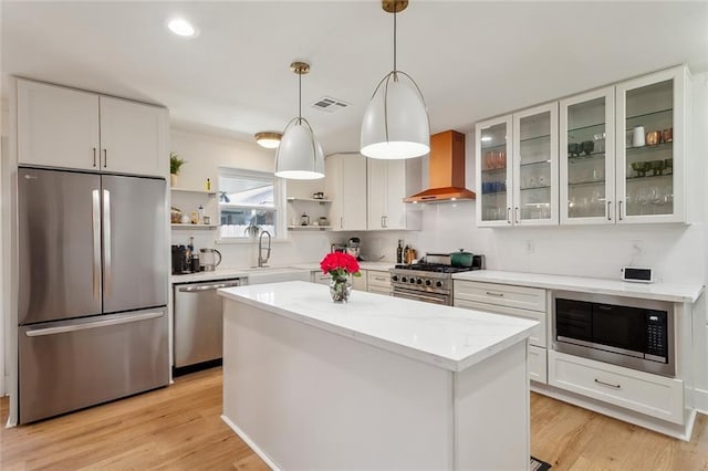 kitchen featuring visible vents, open shelves, a sink, stainless steel appliances, and wall chimney range hood