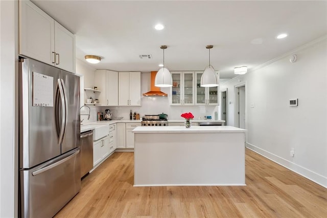 kitchen featuring visible vents, a sink, open shelves, appliances with stainless steel finishes, and wall chimney range hood