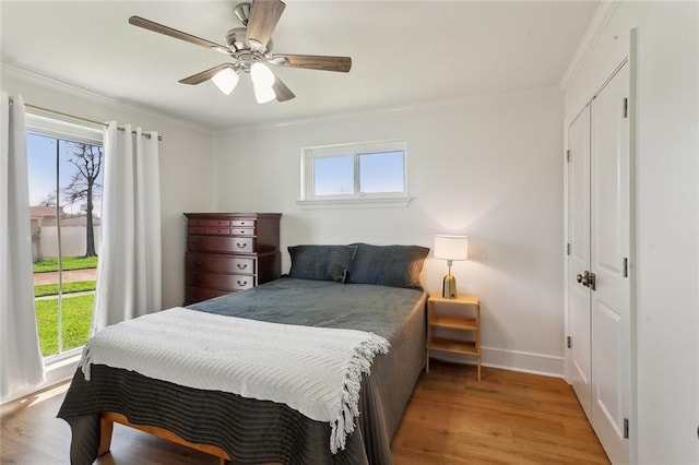 bedroom with a ceiling fan, light wood-style floors, baseboards, and ornamental molding