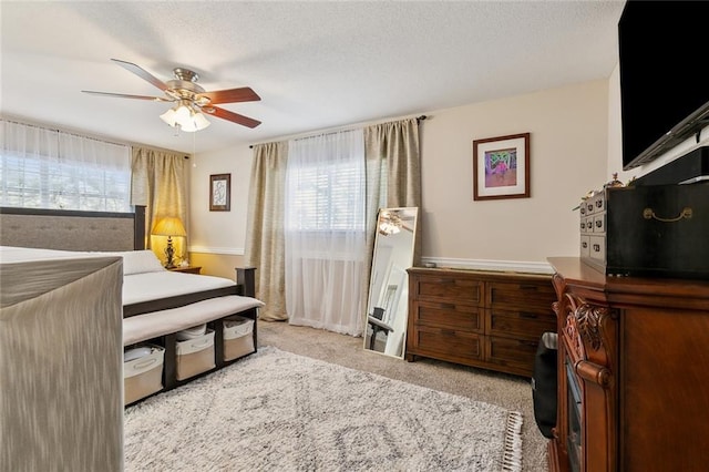 bedroom featuring a ceiling fan, carpet floors, and a textured ceiling