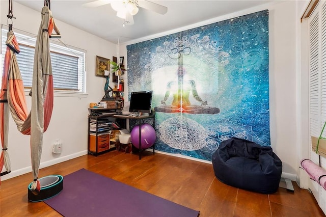 interior space featuring baseboards, wood finished floors, and a ceiling fan