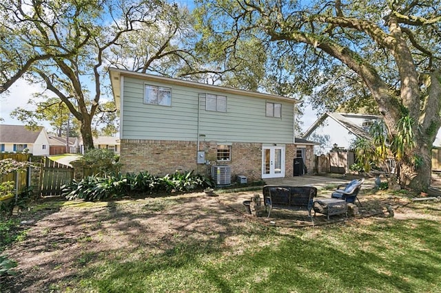 rear view of house with brick siding, french doors, a fenced backyard, and a patio