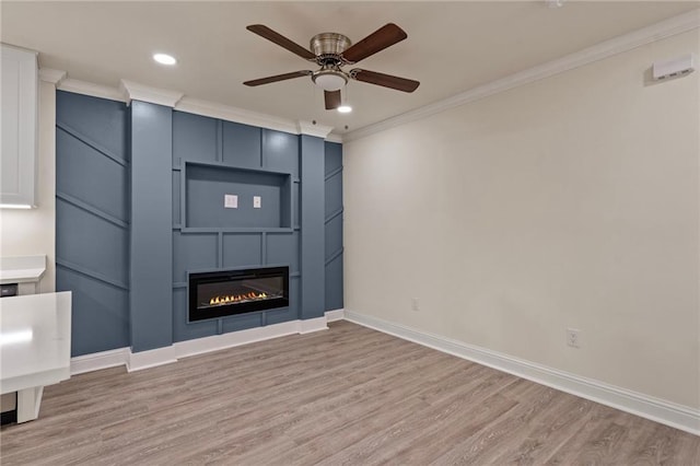 unfurnished living room featuring light wood finished floors, crown molding, ceiling fan, baseboards, and a glass covered fireplace