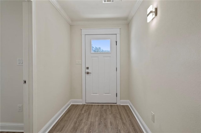 doorway to outside featuring visible vents, baseboards, wood finished floors, and crown molding