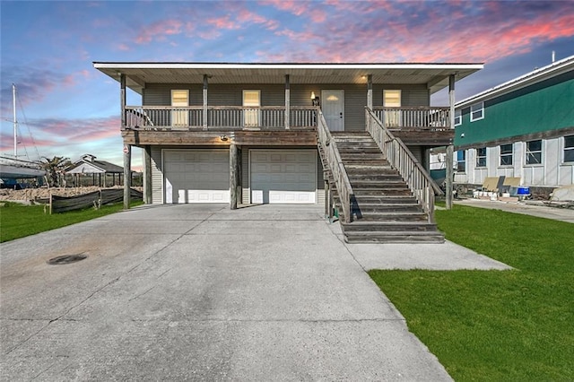 view of front of house featuring driveway, a front lawn, covered porch, a garage, and stairs