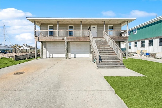 view of front of property with a porch, concrete driveway, a front yard, a garage, and stairs