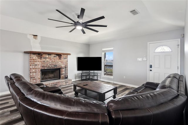 living area with visible vents, baseboards, wood finished floors, and a fireplace