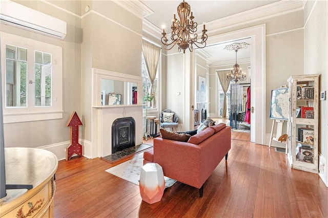 living area with a fireplace with raised hearth, ornamental molding, an AC wall unit, wood-type flooring, and a chandelier