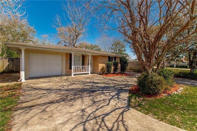 single story home with fence, covered porch, concrete driveway, a garage, and brick siding