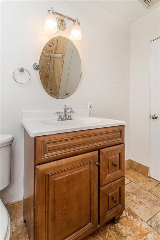 bathroom featuring vanity, baseboards, stone tile flooring, ornamental molding, and toilet