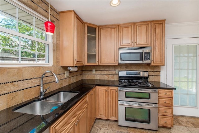 kitchen featuring backsplash, dark stone countertops, stainless steel appliances, and a sink