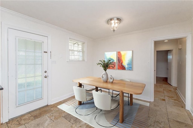 dining space with stone tile floors, crown molding, and baseboards