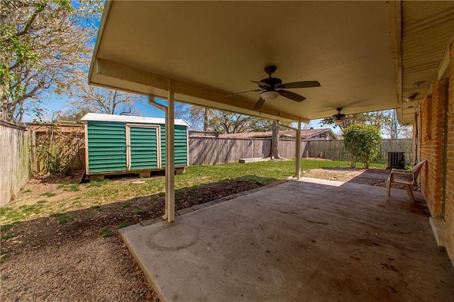 view of patio / terrace with a storage unit, an outbuilding, a fenced backyard, and a ceiling fan