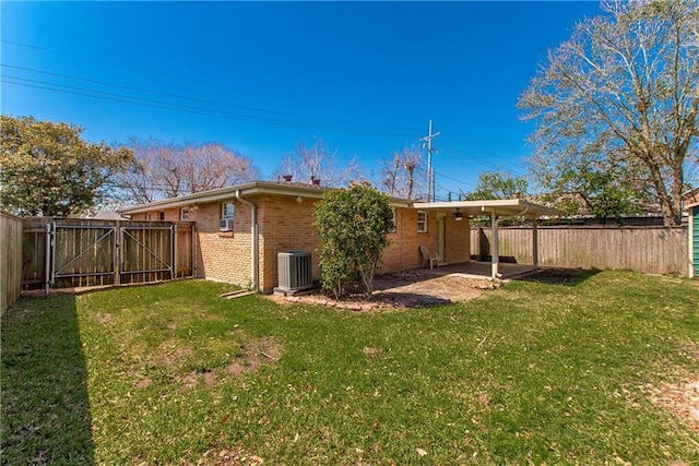 back of property with brick siding, a yard, a fenced backyard, a patio, and a gate