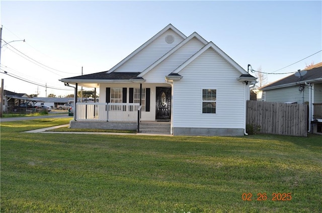 view of front of house with covered porch, a front lawn, and fence