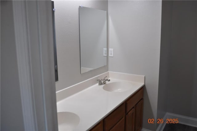 bathroom with double vanity, baseboards, and a sink