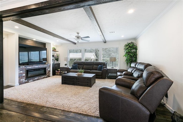 living area with beamed ceiling, a textured ceiling, a glass covered fireplace, crown molding, and baseboards