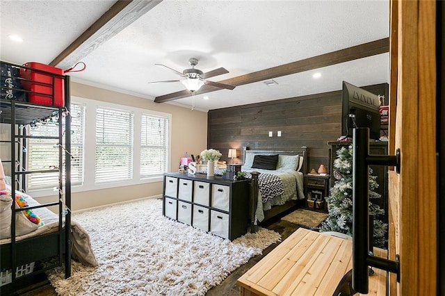 bedroom with beamed ceiling, wood walls, and a textured ceiling