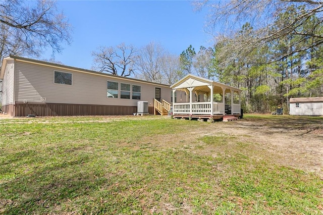 rear view of property featuring central AC unit, a lawn, and a wooden deck