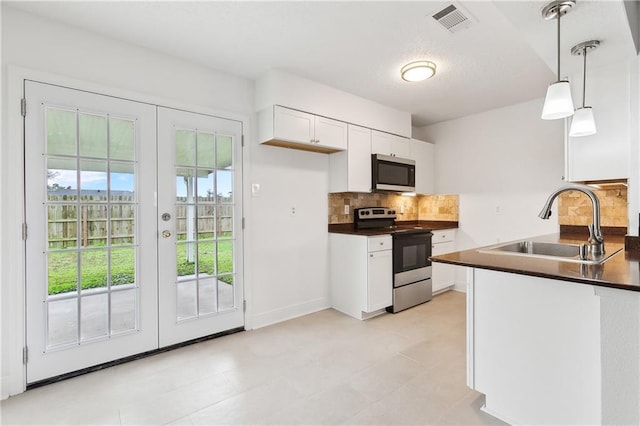 kitchen featuring a sink, backsplash, dark countertops, appliances with stainless steel finishes, and white cabinets