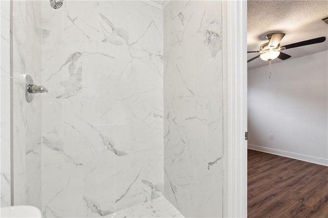 bathroom featuring a marble finish shower, a textured ceiling, baseboards, and wood finished floors