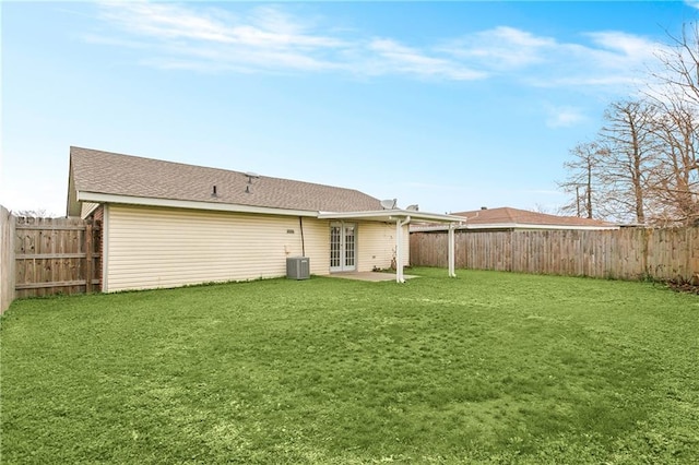 rear view of property with a patio, a yard, a fenced backyard, central AC, and a shingled roof