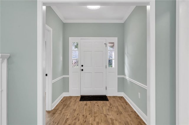 foyer with baseboards, ornamental molding, and light wood finished floors