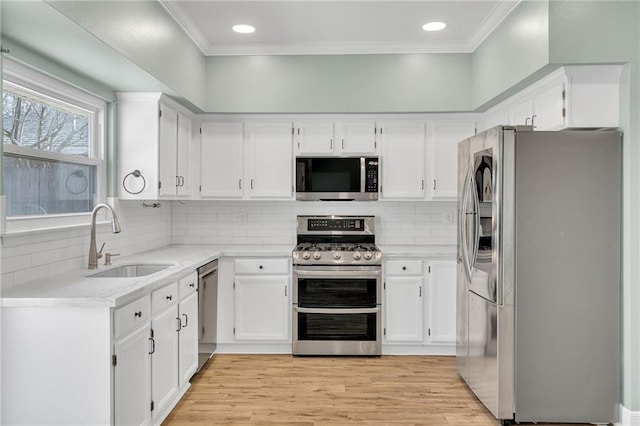 kitchen featuring a sink, crown molding, light wood-style flooring, and stainless steel appliances