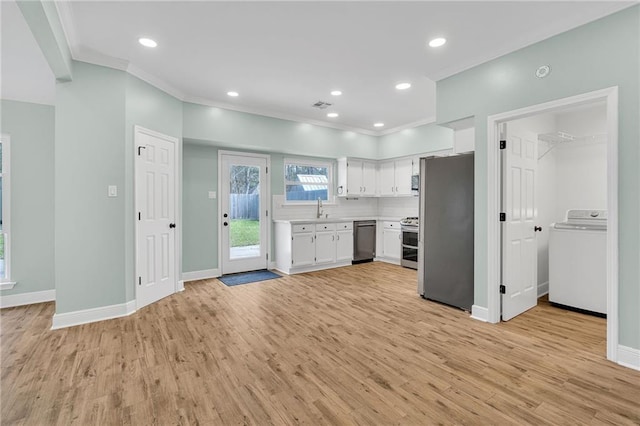 kitchen with light wood-type flooring, stainless steel appliances, washer / dryer, and light countertops