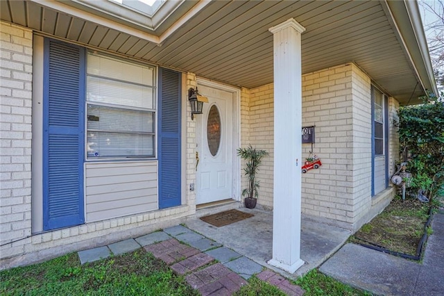 property entrance featuring brick siding and covered porch