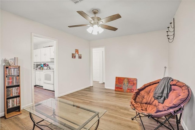 sitting room with ceiling fan, light wood-type flooring, and baseboards