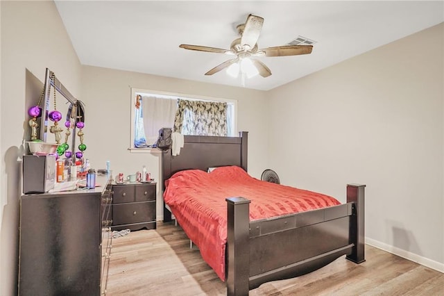 bedroom with visible vents, a ceiling fan, baseboards, and wood finished floors