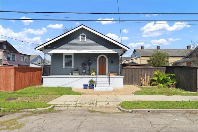 bungalow-style home featuring covered porch and a fenced front yard