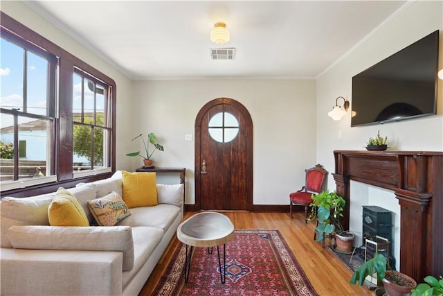 living area with visible vents, ornamental molding, baseboards, and wood finished floors