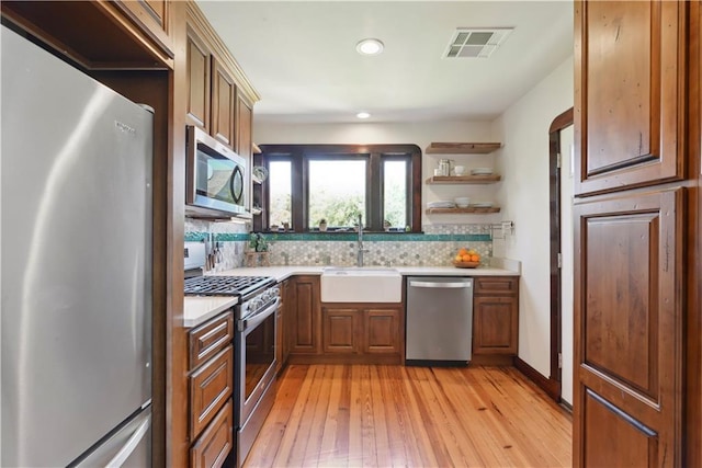 kitchen featuring visible vents, open shelves, a sink, stainless steel appliances, and light countertops