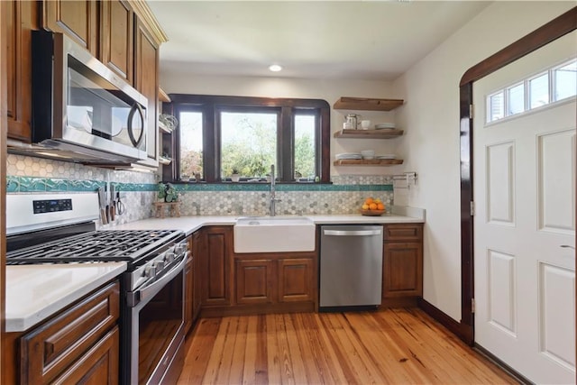 kitchen with a sink, decorative backsplash, appliances with stainless steel finishes, and light countertops