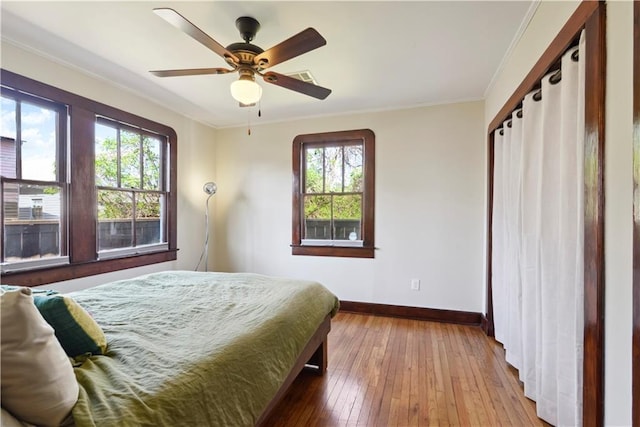 bedroom featuring ornamental molding, ceiling fan, baseboards, and wood-type flooring