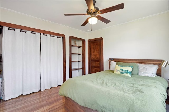 bedroom featuring ceiling fan, wood finished floors, and crown molding