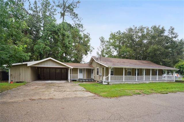 view of front of property featuring driveway, an attached carport, a porch, and a front lawn