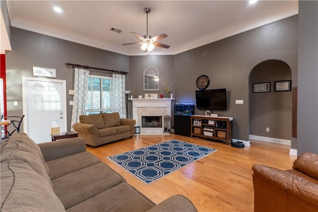 living room featuring visible vents, ornamental molding, wood finished floors, arched walkways, and baseboards