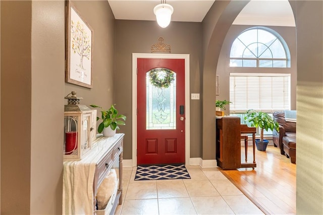 foyer entrance featuring light tile patterned flooring, a healthy amount of sunlight, and baseboards